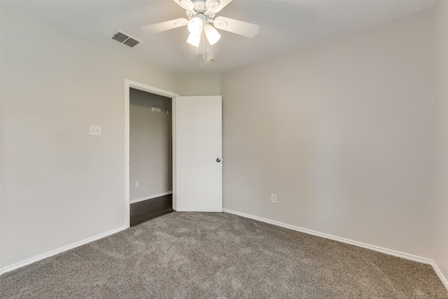 spare room with carpet flooring, ceiling fan, baseboards, and visible vents