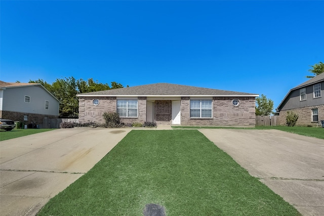 view of front of home with a front lawn, fence, brick siding, and roof with shingles