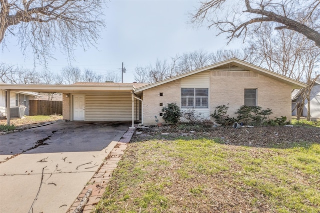 view of front of property with a carport, fence, brick siding, and driveway