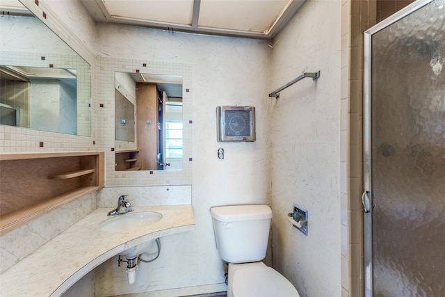 full bath featuring toilet, a stall shower, backsplash, and a sink