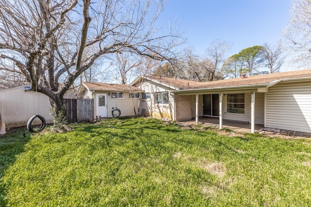 rear view of property with a yard, a patio, and fence