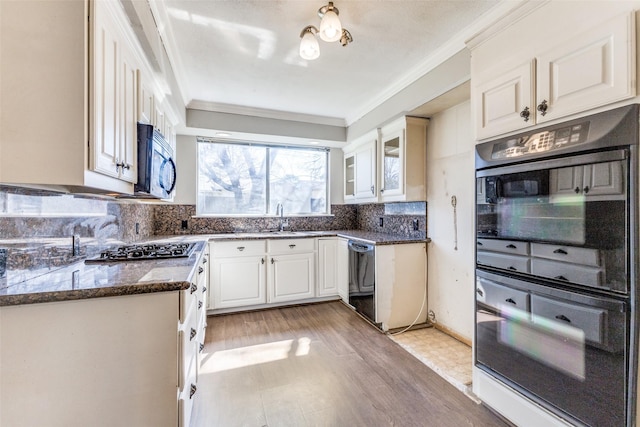 kitchen with dark stone countertops, a sink, ornamental molding, black appliances, and tasteful backsplash