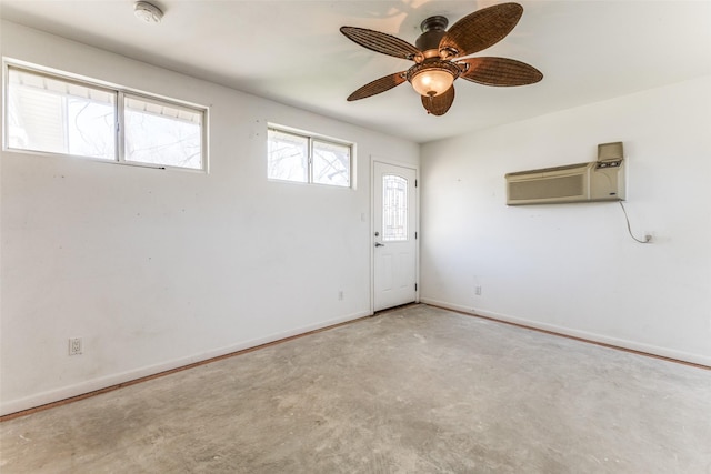 entrance foyer with baseboards, ceiling fan, unfinished concrete floors, and a wall mounted AC