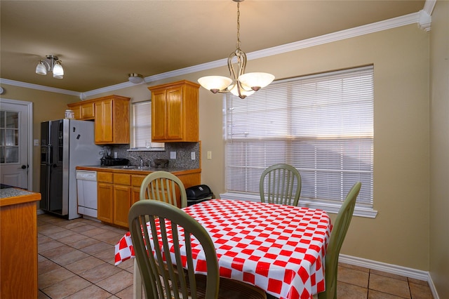 dining area featuring an inviting chandelier, crown molding, light tile patterned floors, and baseboards