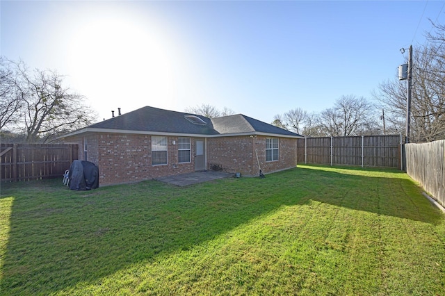 rear view of house featuring brick siding, a fenced backyard, and a yard