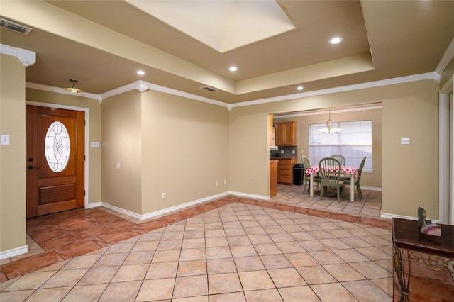 foyer entrance with light tile patterned flooring, visible vents, a tray ceiling, and ornamental molding