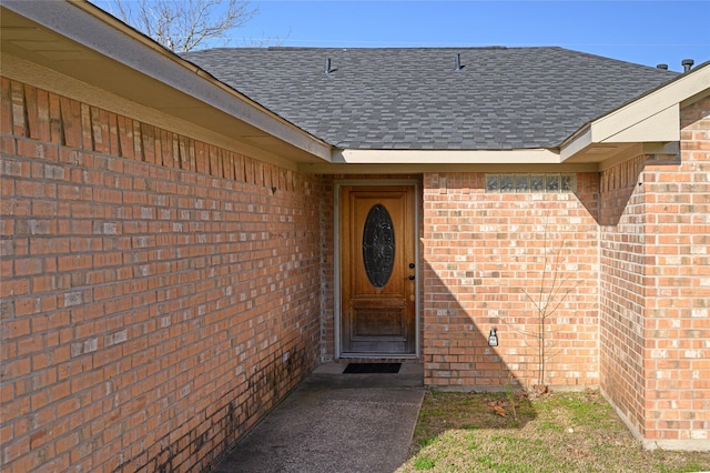 property entrance featuring brick siding and roof with shingles