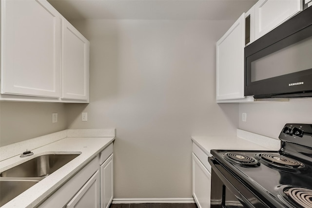 kitchen featuring white cabinets, black appliances, baseboards, and a sink