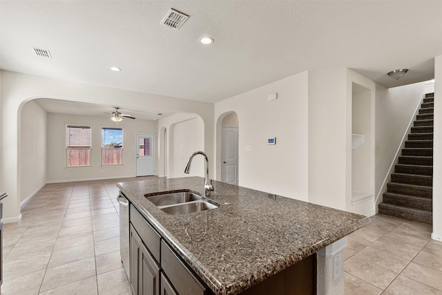 kitchen featuring arched walkways, visible vents, stainless steel dishwasher, and a sink