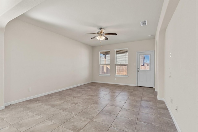 empty room with light tile patterned flooring, baseboards, visible vents, and ceiling fan