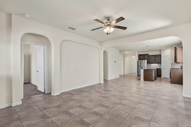 unfurnished living room with visible vents, baseboards, recessed lighting, arched walkways, and a ceiling fan