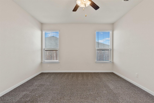 spare room with baseboards, a healthy amount of sunlight, ceiling fan, and dark carpet