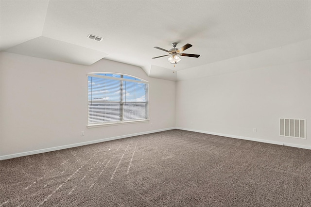 carpeted spare room featuring visible vents, baseboards, ceiling fan, and vaulted ceiling