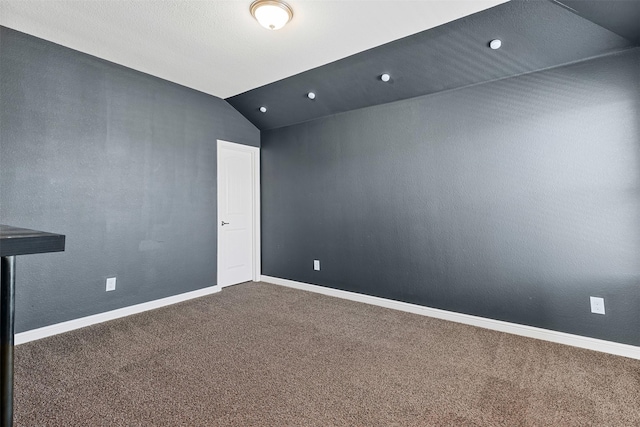 carpeted spare room with baseboards and vaulted ceiling