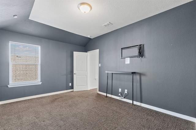 interior space featuring baseboards, visible vents, lofted ceiling, a textured ceiling, and carpet flooring