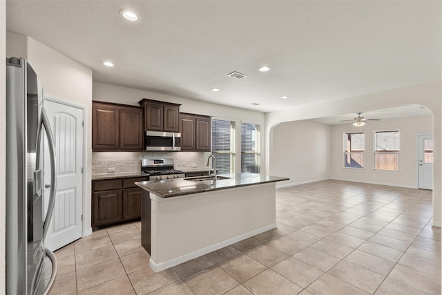 kitchen featuring visible vents, a sink, backsplash, stainless steel appliances, and arched walkways