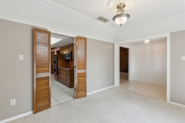 unfurnished room with light carpet, light tile patterned floors, baseboards, and visible vents