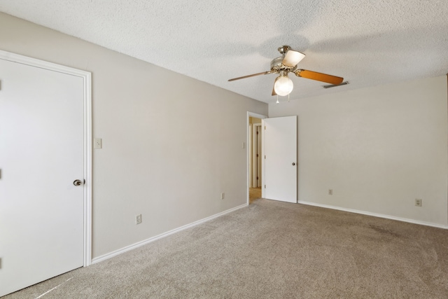 carpeted spare room with baseboards, a ceiling fan, visible vents, and a textured ceiling