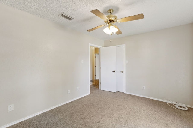 unfurnished room with visible vents, baseboards, carpet, a textured ceiling, and a ceiling fan