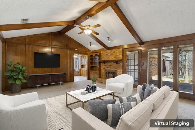 carpeted living room featuring a ceiling fan, a textured ceiling, wood walls, a brick fireplace, and vaulted ceiling with beams