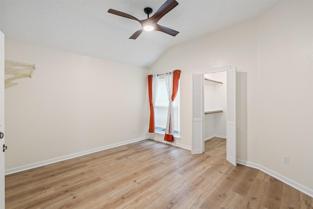 unfurnished bedroom with baseboards, light wood finished floors, a ceiling fan, and vaulted ceiling