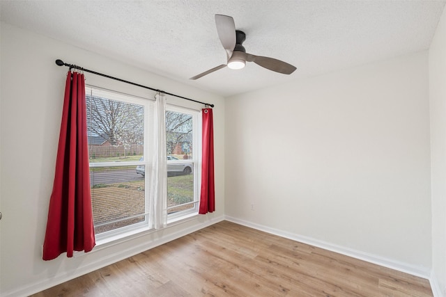 empty room featuring baseboards, a textured ceiling, a ceiling fan, and light wood finished floors