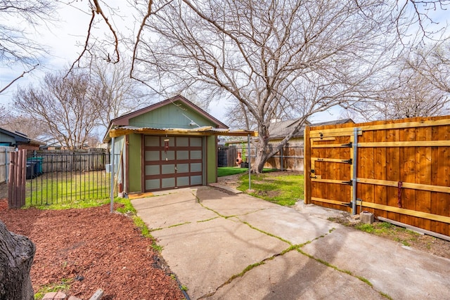 detached garage featuring concrete driveway, a gate, and fence