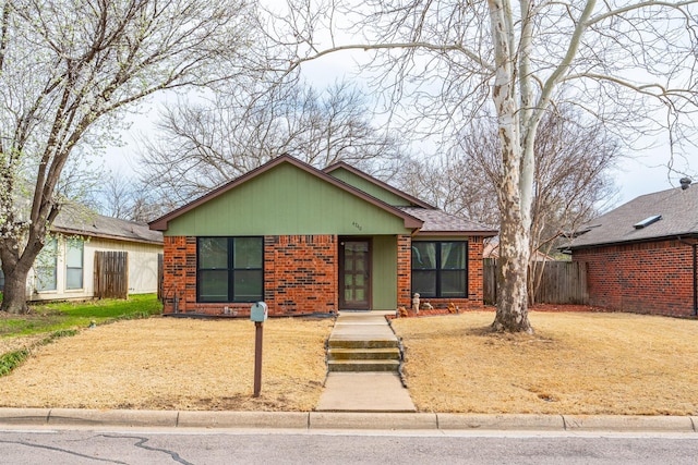 view of front of house featuring fence and brick siding