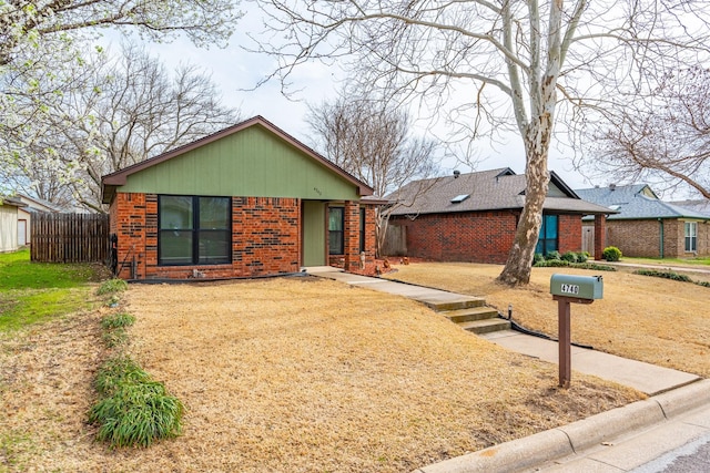 view of front of property featuring brick siding, a front lawn, and fence