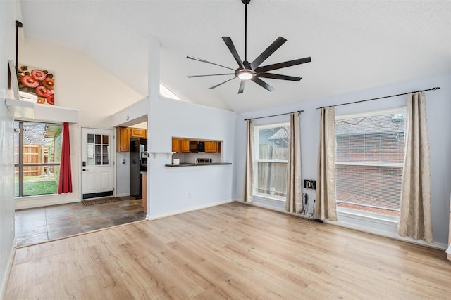 unfurnished living room featuring high vaulted ceiling, light wood-style floors, baseboards, and ceiling fan