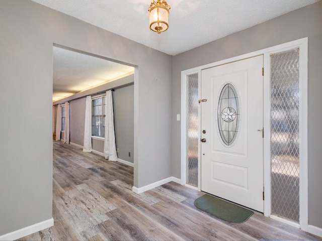 entryway featuring wood finished floors, baseboards, and a textured ceiling