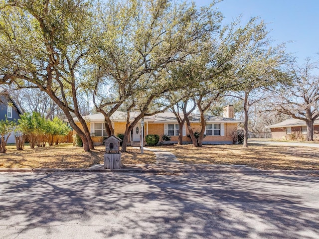 single story home with a chimney and driveway