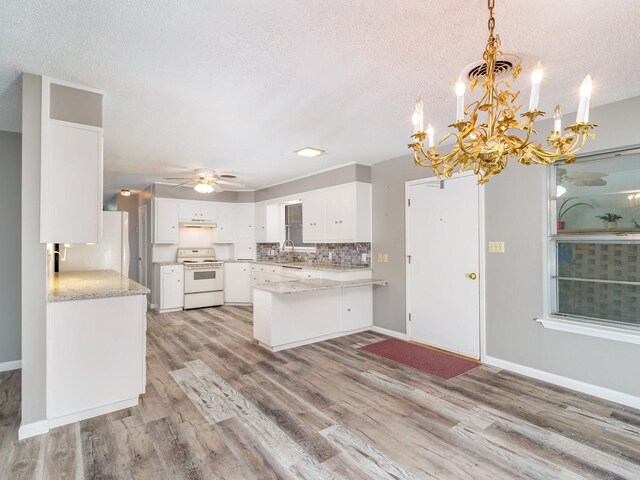 kitchen featuring visible vents, under cabinet range hood, light wood-style flooring, a peninsula, and white appliances