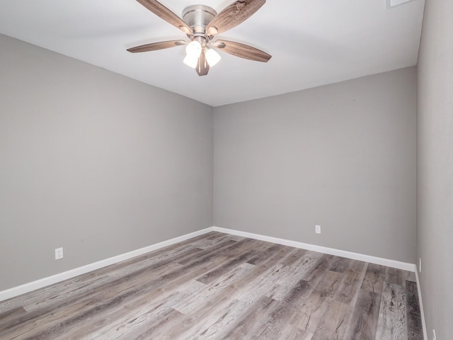 spare room with a ceiling fan, wood finished floors, and baseboards