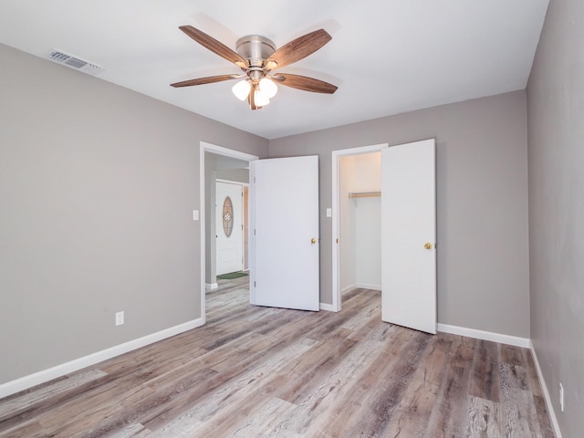 unfurnished bedroom featuring visible vents, ceiling fan, baseboards, wood finished floors, and a closet