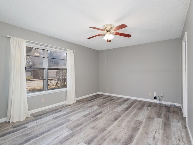 unfurnished room with baseboards, wood finished floors, and a ceiling fan