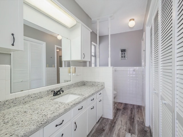 bathroom with a closet, toilet, tile walls, and wood finished floors