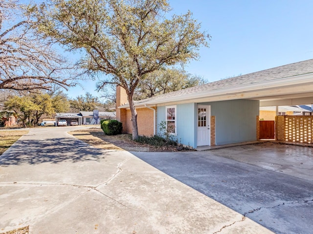 view of home's exterior with a carport, concrete driveway, and a chimney