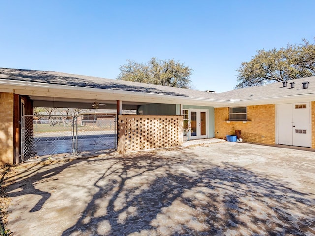 rear view of house with a carport, french doors, brick siding, and roof with shingles