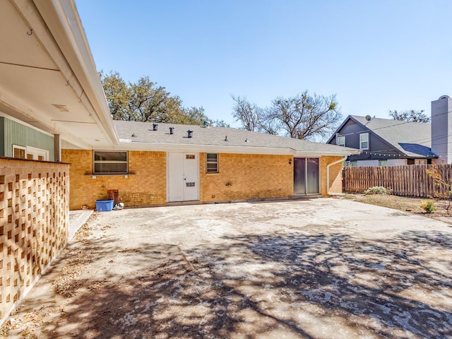 rear view of property featuring a patio area, fence, and brick siding