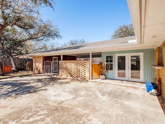 exterior space featuring french doors and a shingled roof