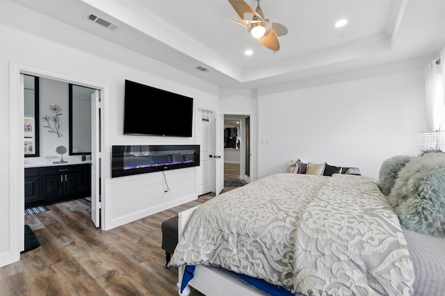 bedroom with visible vents, recessed lighting, a tray ceiling, and wood finished floors