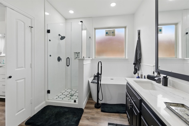 bathroom with a stall shower, wood finished floors, recessed lighting, a freestanding bath, and vanity