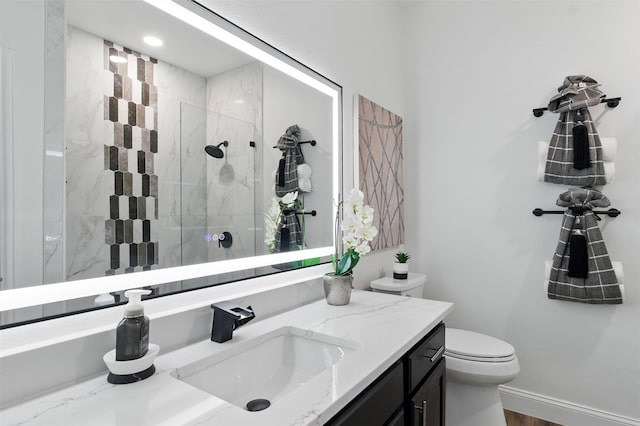 bathroom with a shower stall, toilet, vanity, and baseboards