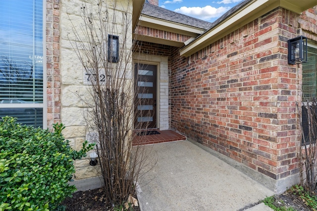 doorway to property featuring brick siding and a garage