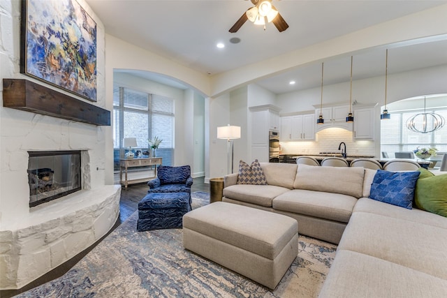 living room featuring wood finished floors, a healthy amount of sunlight, a fireplace, and a ceiling fan