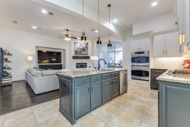 kitchen featuring white cabinetry, open floor plan, appliances with stainless steel finishes, and a sink