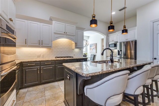 kitchen with visible vents, a breakfast bar, a sink, appliances with stainless steel finishes, and backsplash