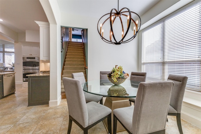 dining room featuring arched walkways, stairway, baseboards, and an inviting chandelier