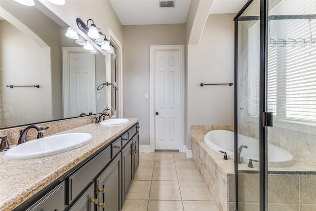 bathroom with tile patterned flooring, double vanity, a bath, and a sink